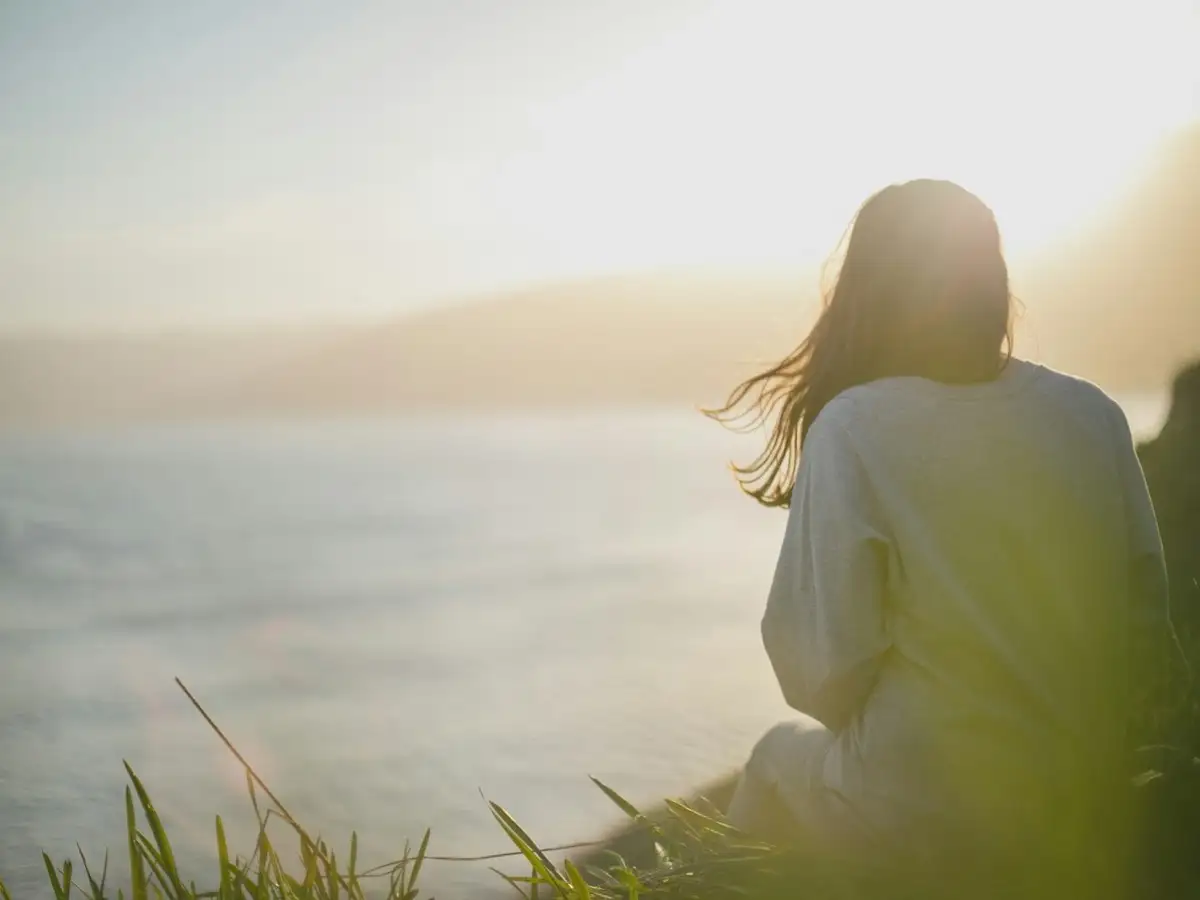 Person facing the sea, taking a calming breath