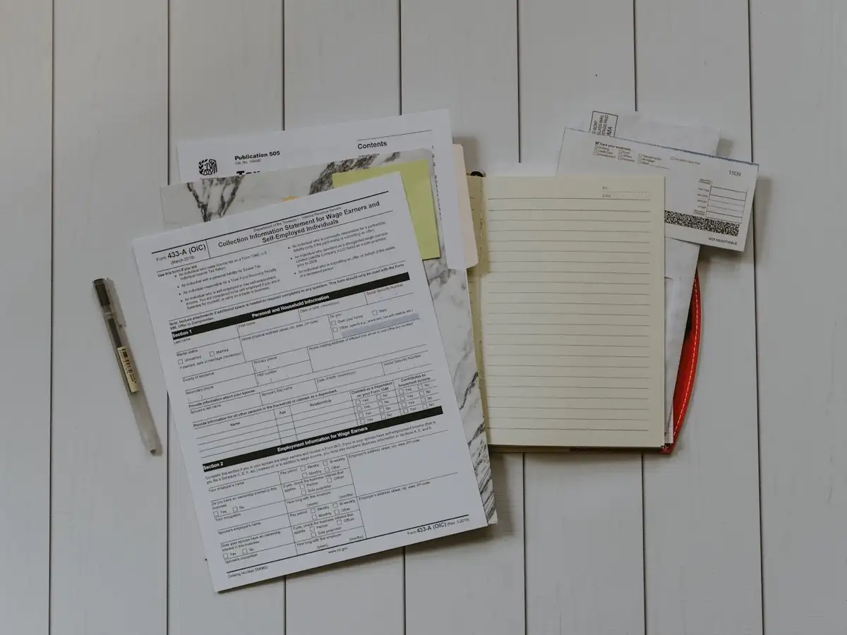 Papers and documents placed beside a laptop