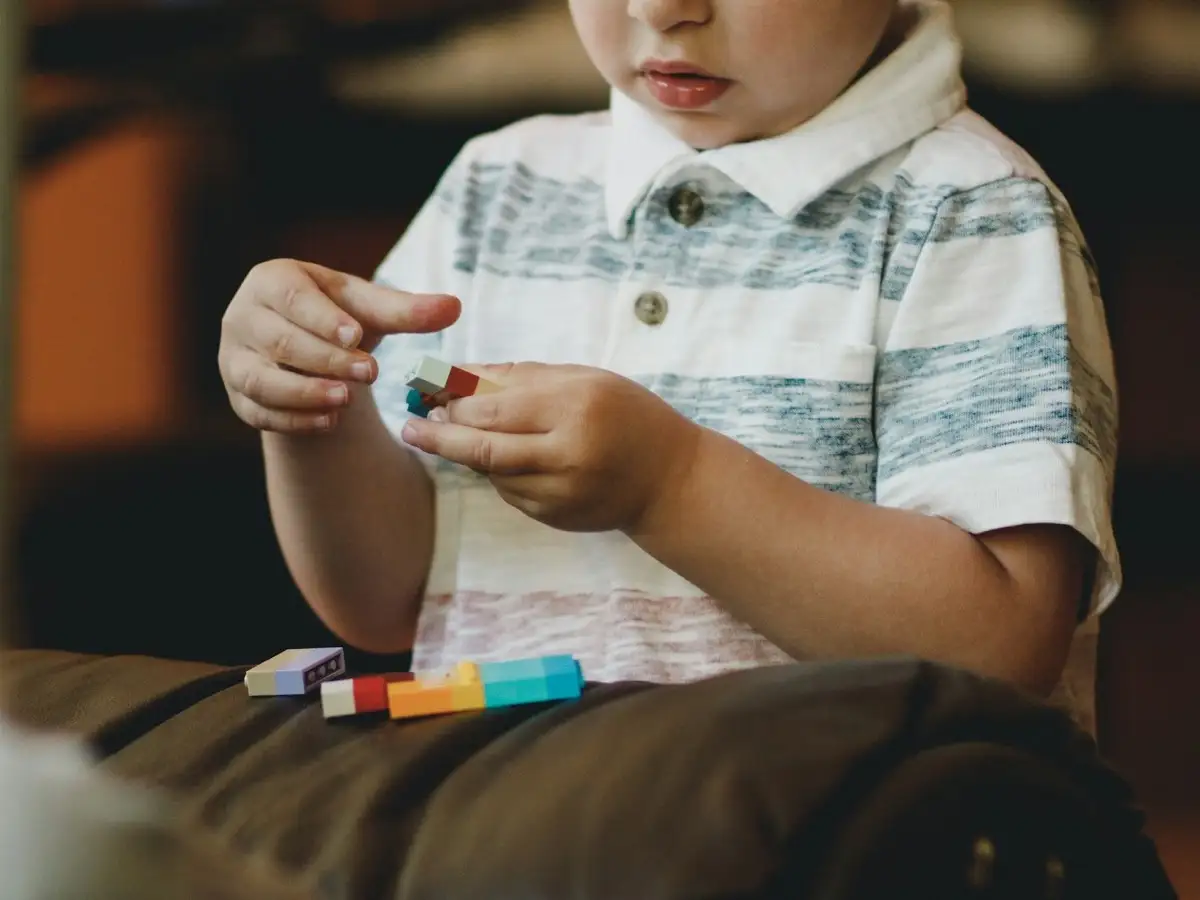 Child focused on playing with colorful toy blocks