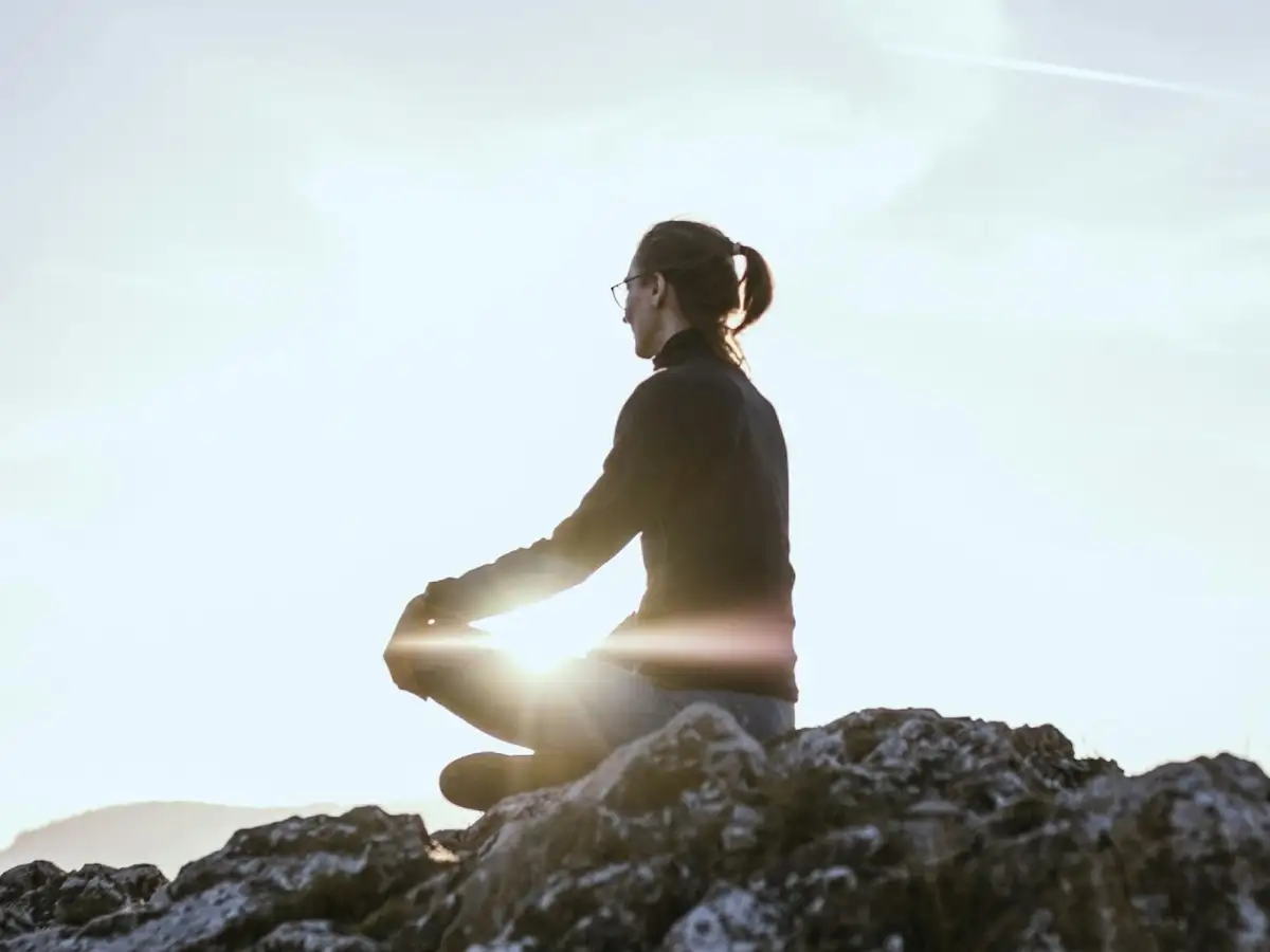 Person sitting quietly outdoors, taking a moment to reflect