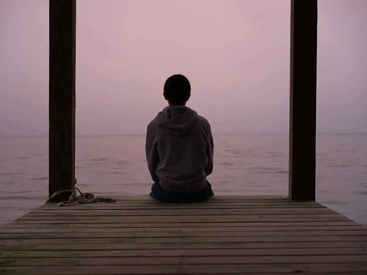 Person sitting quietly on a rock, reflecting