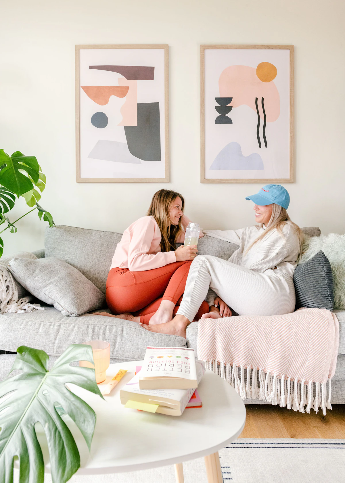 Two friends talking closely on a couch, one listening while the other speaks — a warm, structured conversation