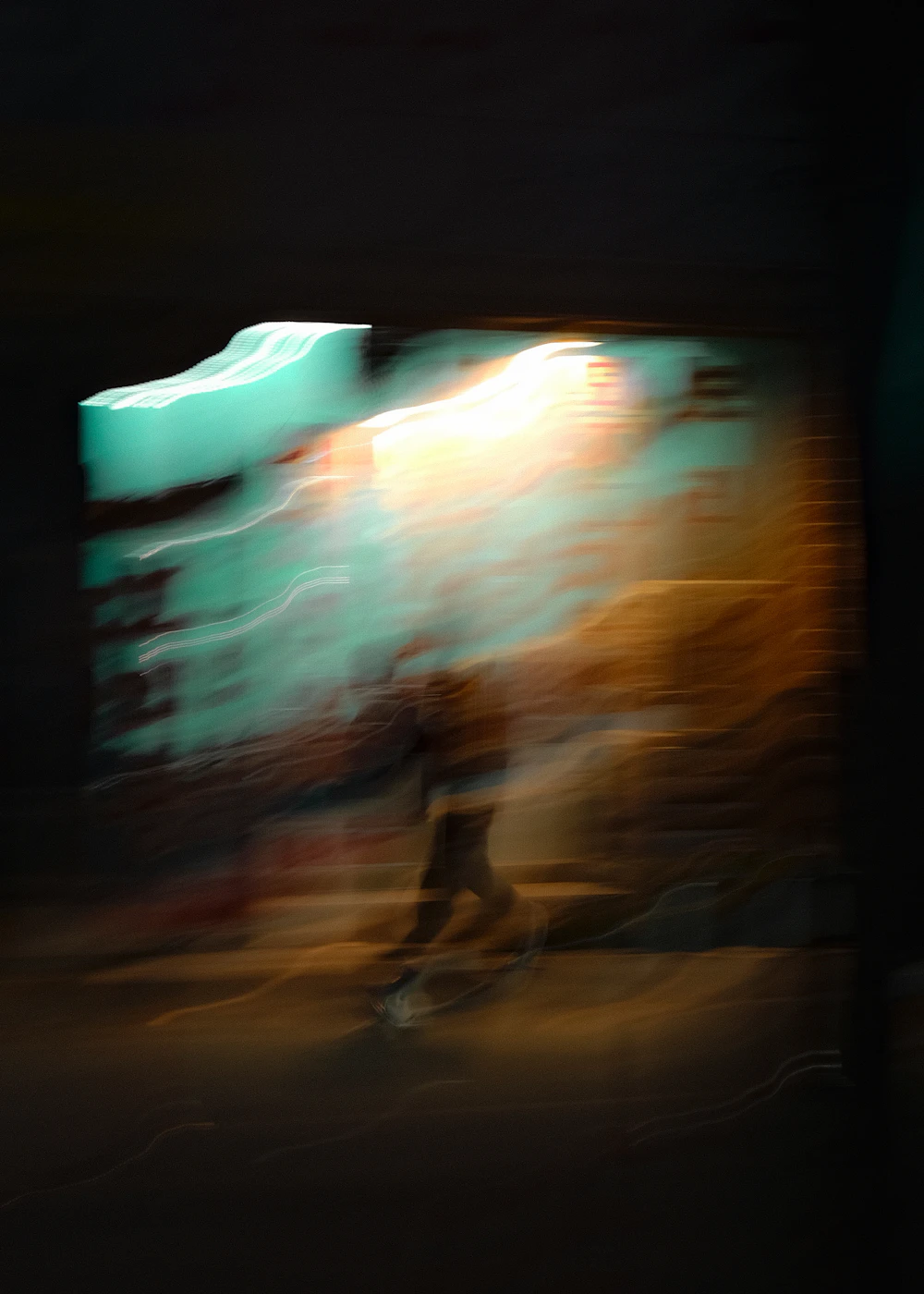 A blurred figure walking in front of a bright wall, evoking something undefined