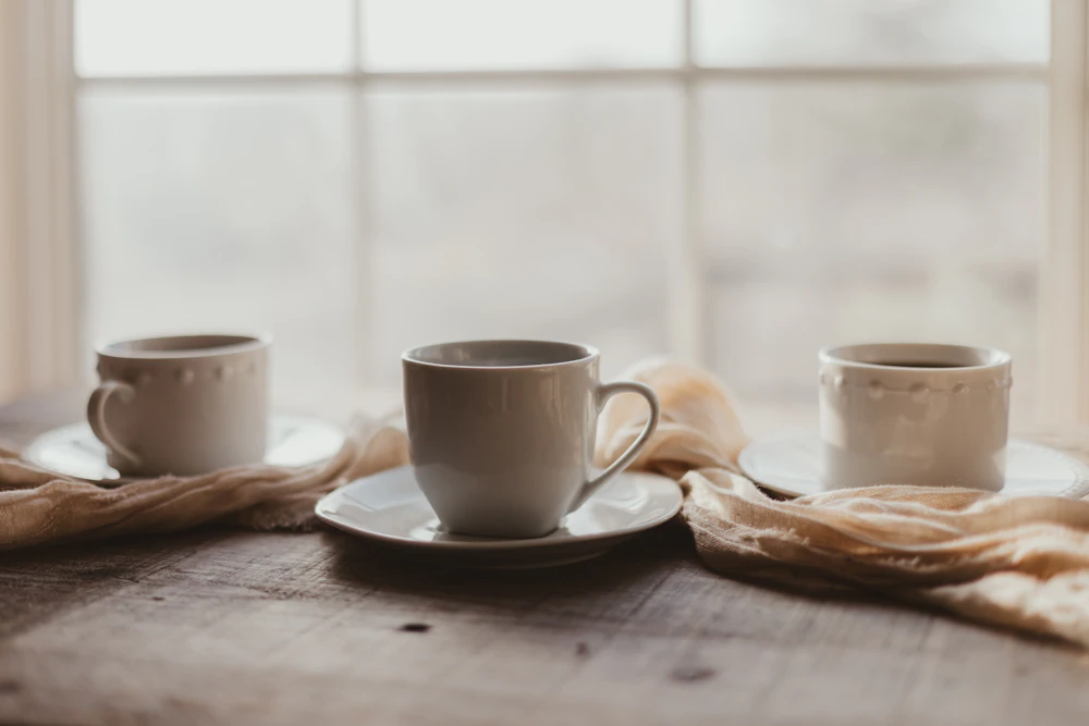Two coffee cups sitting on a wooden table, one now sitting alone