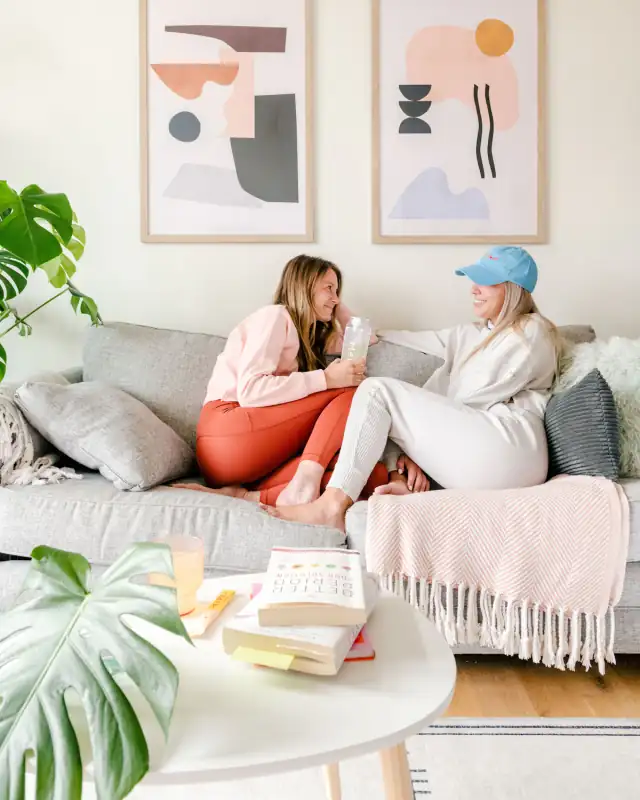 Two friends talking on a sofa under a blanket