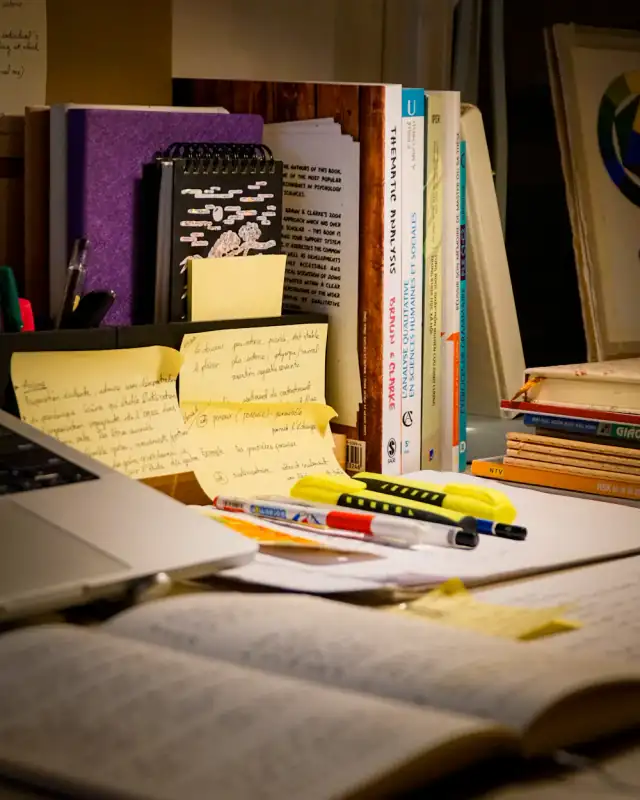 A cluttered desk with sticky notes and books