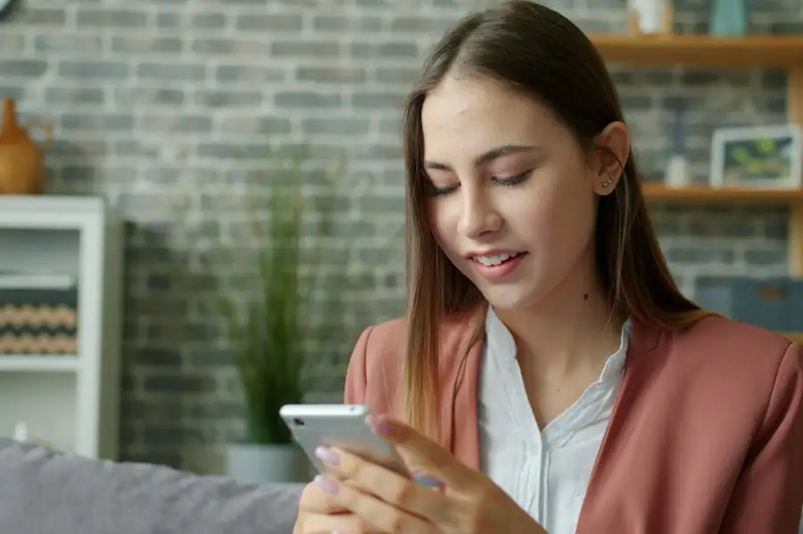 Young woman smiling as she checks her phone after being matched with a coach at Ventoutt