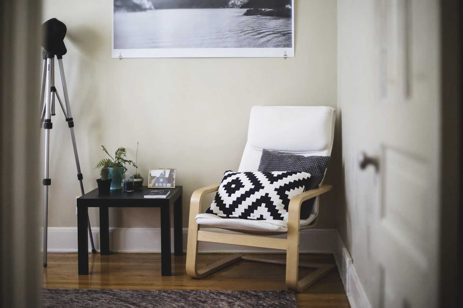 A quiet corner of a room with an armchair, a cushion and a small side table