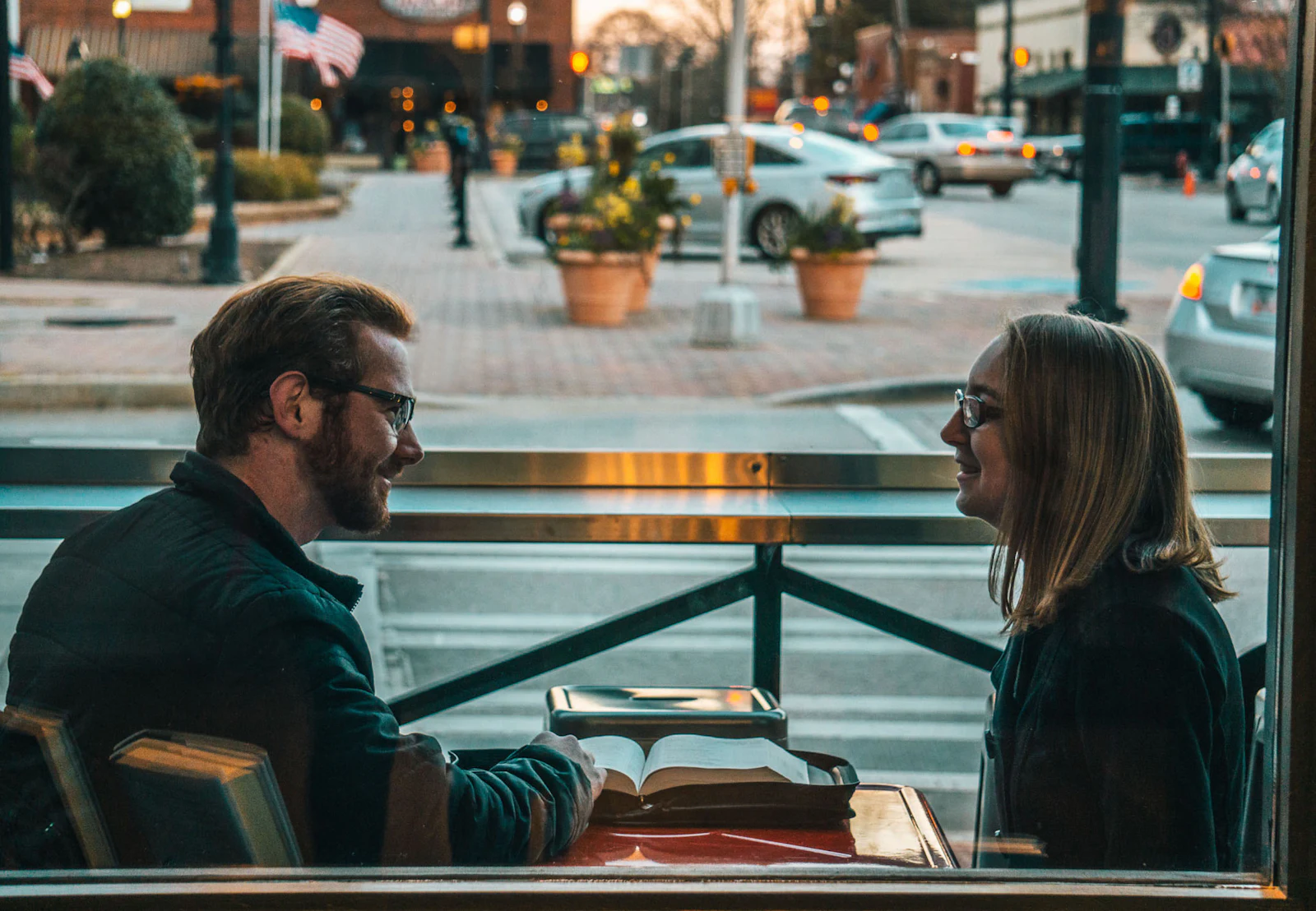 A man and a woman sitting across from each other, talking in daylight