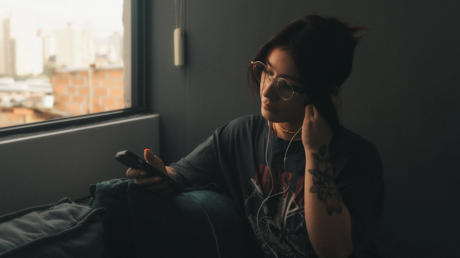 A woman on a sofa with her phone, lost in thought