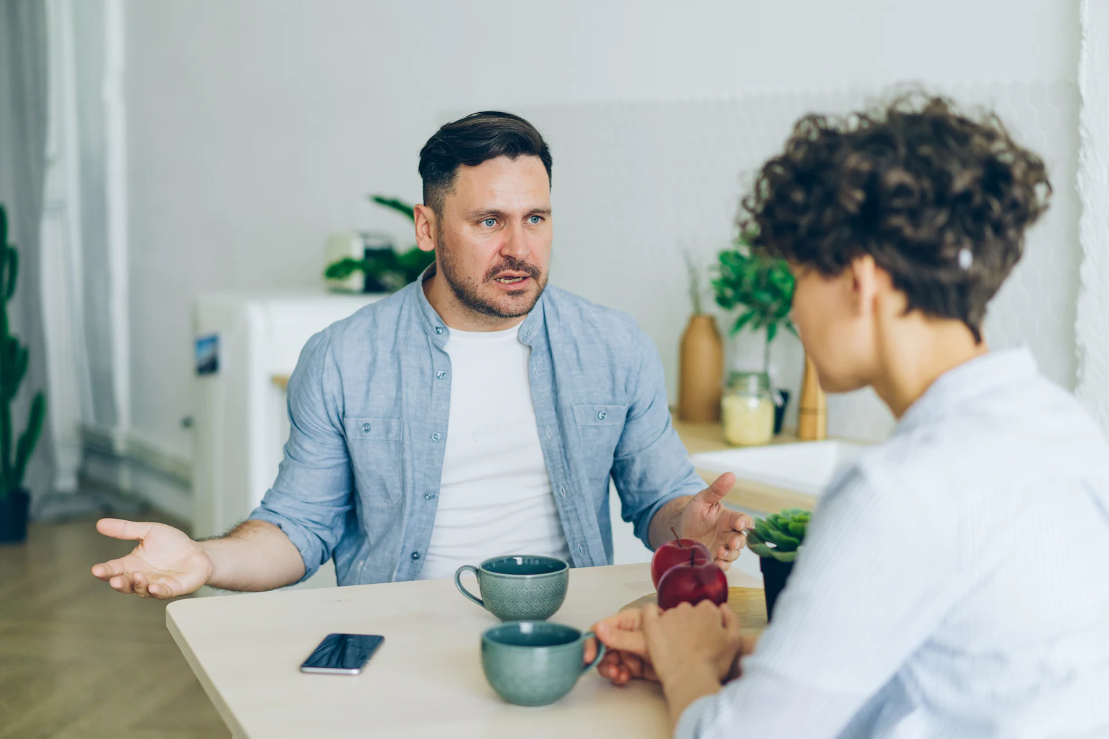 A man gesturing as he talks with a woman at a table