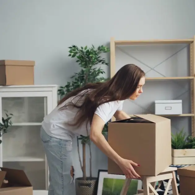 Young woman packing boxes while moving into a new home, representing life transitions and career coaching for young professionals
